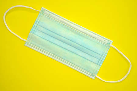 Antibacterial medical mask of blue color on a yellow background. Coronavirus Protection concept....