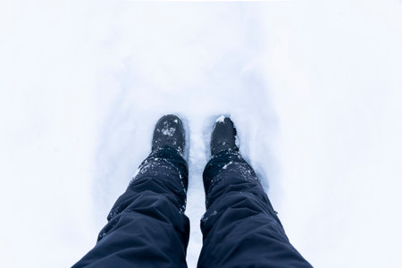 Snowy Boots. Top view of shoes or boots footprint in fresh snow. Winter season. Focus on Legs. High...