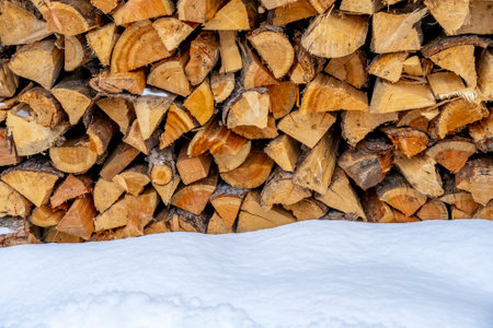 Stack of wood with lots of dry wood near the wall of a house in the winter on snow. High quality photoの写真素材