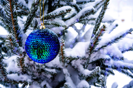 Tidewater green Christmas ball hangs on a snow-covered branch of a Christmas tree. Blue light bokeh background. New Year, greeting and holiday card, banner. High quality photoの写真素材