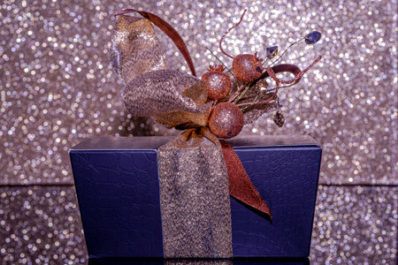 Gift box with big golden rose bow and crystal decorations on a blurred rose background. Valentines...
