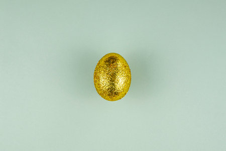 Trendy easter background with shiny golden colored egg. Creative spring holiday image with painted chicken egg. Top view flat lay still life. Easter conceptの写真素材