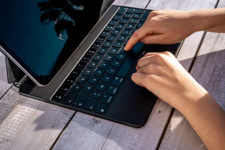 Nice, France - 01.29.2021: New iPad Pro 12.9 inches from Apple on a light background. Tablet Computer on a Wooden background. Boy teenager pressing keys on Apple iPad. High quality photo.のeditorial素材