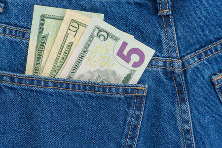 American dollars in jeans pocket background. Cash, money is in the pocket of blue jeans. Close-up