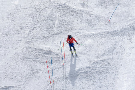 Auron, FRANCE - 23.02.2021: Skier descends the mountain. Sportsman glides downhill along the snowy slope of a ski resort. The concept of winter sports.のeditorial素材