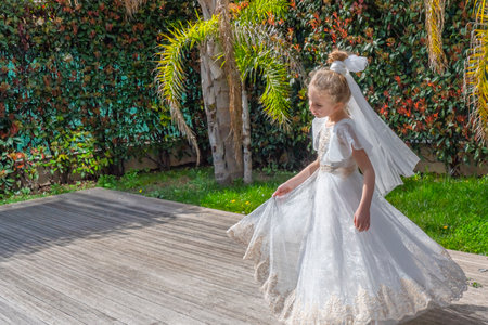 Emotional beautiful blonde girl in a fashionable white tulle dress is dancing on the palm garden near the swimming pool. Romantic concept. High quality photoの写真素材