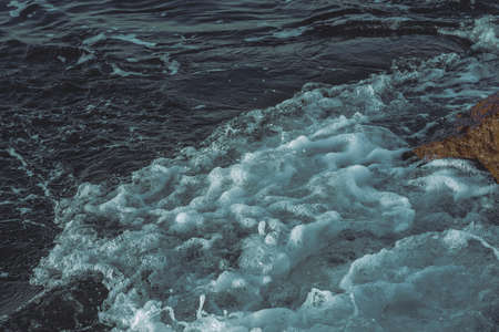 Waves crushing on the rocks on beach in the evening time. Special green filter.