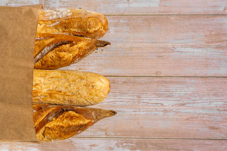 French traditional baguettes in paper bags on wooden table background. High quality photo