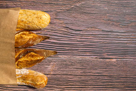 French traditional baguettes in paper bags on wooden table background. High quality photoの写真素材