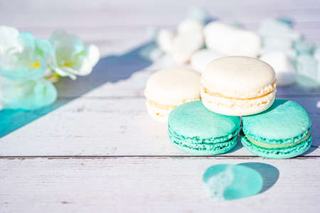Selective focus. Turquoise and white macarons on light wooden background. French Pastel Macaroons. Blurred focus.の写真素材