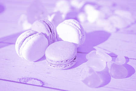 Aesthetic blurred photo with special filter. Lavender light color macarons on wooden background. French Pastel Macaroons. Selective focus. High quality photoの写真素材