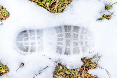 Frozen footprints in the snow. Melting snow during the thaw in the spring background. High quality photoの写真素材