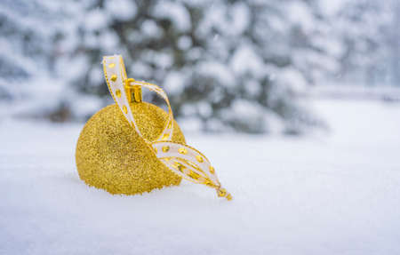 Christmas golden ball with ribbon on abstract cold winter background with snowflakes. High quality photoの写真素材