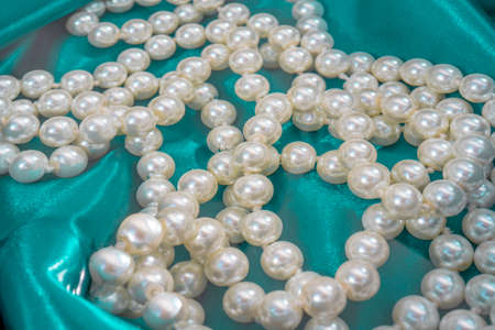 Natural White Pearls in the water on a blue silk texture close-up. Pendants on the neck. High...
