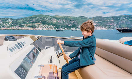 Captain boy drives the yacht. Travel adventure concept. Yachting with child on summer vacation. Hight quality photoの写真素材