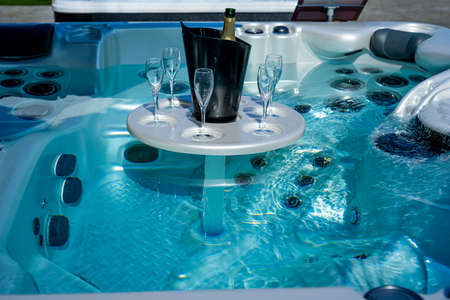 A bottle of champagne in a black ice bucket and glasses on the table in the water tube bath. Soft focus backgroundの写真素材