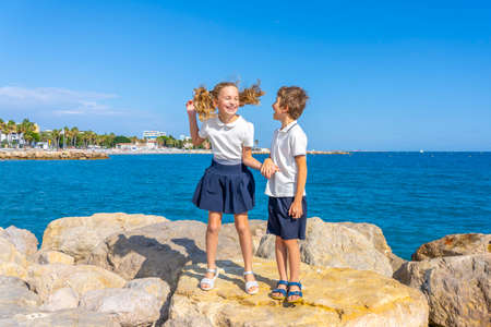 School boy and girl jumping on a rocks near sea. After school activities. High quality photoの写真素材