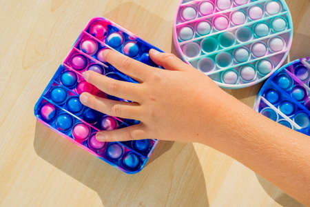Little child playing with anti stress sensory pop up at wooden table.