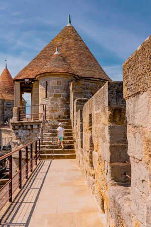 Carcassonne, France - 02.07.2021: Fortified walls with a boy walking away. Medieval castle of Carcassonne town. High quality photoのeditorial素材