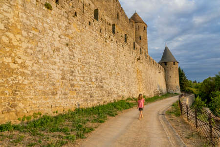 Carcassonne, France - 02.07.2021: Fortified walls with a girl walking away. Medieval castle of Carcassonne town. High quality photoのeditorial素材