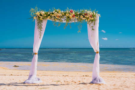 Wedding arch of flowers on the sky background, wedding ceremony of a tropical beach. High quality photoの写真素材