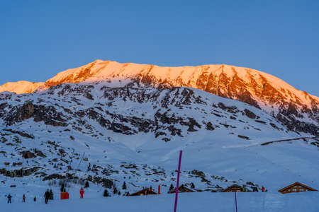 Alpe dHuez, France - 30.12.2021 : Winter landscape on alpine mountains resort in the evening. Skiing people on the ski slop. High quality photoのeditorial素材