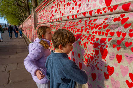 Westminster, London UK - 20.04.2022: The children looking at the National COVID Memorial Wall painted with red hearts with the names, dates of death of Covid victims. High quality photo.のeditorial素材