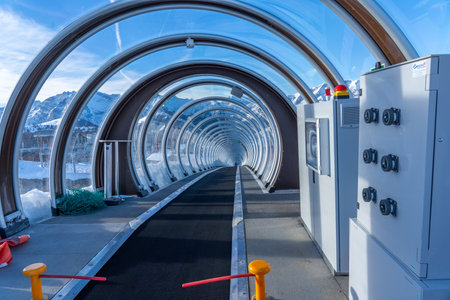 Alpes d'Huez, France - 31.12.2021: Magicagic carpet ski lift in a glass tunnel. Snowy winter day in the french ski resort. Hight quality photoのeditorial素材