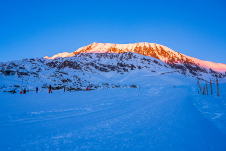 Alpe d'Huez, France - 30.12.2021: Winter landscape on alpine mountains resort in the evening. Skiing people on the ski slop. High quality photoのeditorial素材