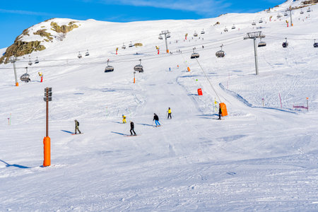 Alpe D'Huez, France - 31.12.2021: Skiers skiing, chairlifts in Alpine ski resort on bright winter day. Winter holiday, family recreation in snow mountains. High quality photoのeditorial素材