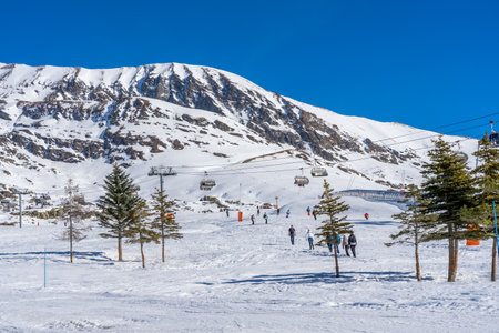 Alpe D'Huez, France - 01.01.2022: Skiers skiing, chairlifts in Alpine ski resort on bright winter day. Winter holiday, family recreation in snow mountains. High quality photoのeditorial素材