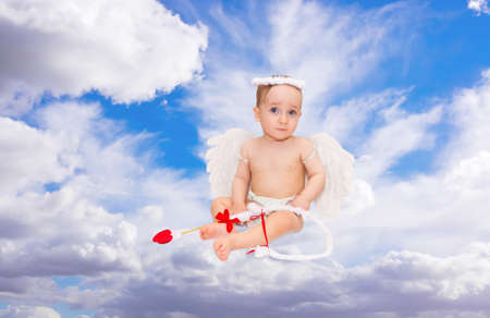 Cute little boy dressed as Cupid on blue sky の写真素材