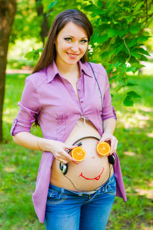 Pregnant woman belly with smiley face. Unborn baby listening music in the belly of his motherの写真素材