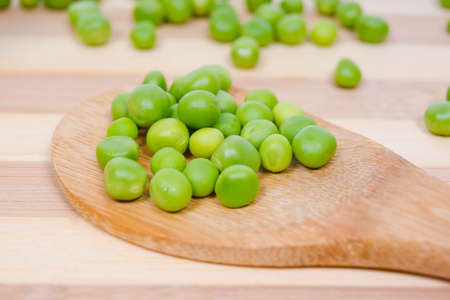 Wooden spoon with seeds of green peas on the kitchen tableの写真素材