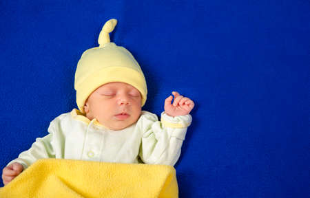 Pretty newborn little boy sleeping in crib with toys. Baby goods packaging template. Closeup portrait of newborn baby with smile on face. Healthy and medical concept. Eco conception. Nursery.の写真素材