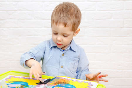 Cute young kid boy drawing or painting fingers. Kindergarten children education, back to school, or...