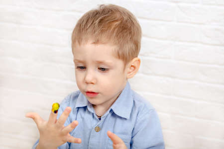 Funny cheerful child drawing with fingers in album using special paint. Creativity concept