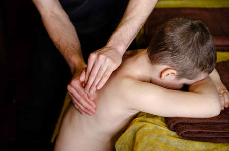 Chiropractic, osteopathy, dorsal manipulation. Therapist doing healing treatment on mans back . Alternative medicine, pain relief concept. A teenage boy is given a medical massage of the back and neckの写真素材