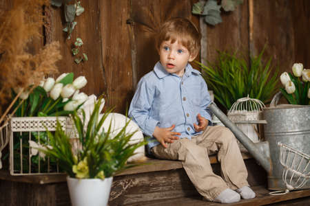 Surprised baby boy playing with Easter bunny in a green grass. Rustic decoration. Studio shot on a...