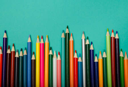 Colorful multicolor pencils arranged in a wave isolated over blue background. Back to school....