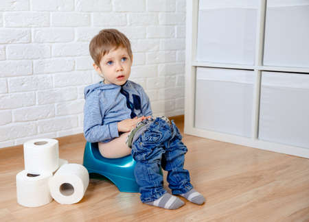 Sick baby constipation, colic, bloating, indigestion heartburn, digestion, pain, diarrhea. Child sitting on the potty with toilet paperの写真素材