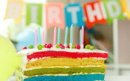 Appetizing birthday cake with colorful candles. Festive colorful background. Birthday party and wishes conceptの写真素材
