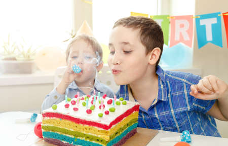 Beautiful kids celebrating birthday and blowing candles on homemade baked cake, indoor. Birthday...