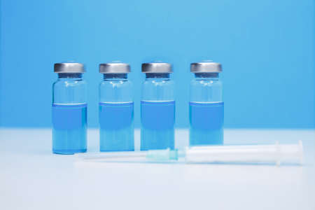 Glass medicine vials on blue background. Healthcare cure concept. Coronavirus, Covid 19 virus, vaccine vialの写真素材