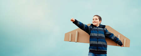 Happy boy with paper airplane against blue sky background outdoors. Concept of successful business developmentの写真素材