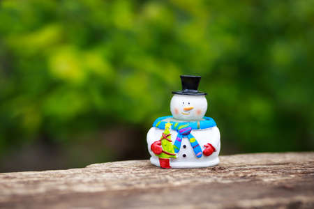 Christmas background with snowman. Beautiful winter background with snowman on a wooden old desk, fir trees. Winter and New Year concept. Greeting card with green background, holiday wallpaperの写真素材