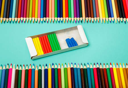 Back to school. Color pencils and modeling clay on blue background. Plasticine. Close up. Top view,...