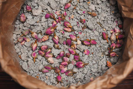 Sea-salt and dried roses closeup. Natural cosmetics with flowers and herbs for homemade spa on wooden background top view. Flat lay with sea salt on dark surface. Mockup. Spa conceptの写真素材