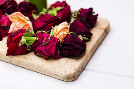 Dried violet rosebuds on wooden blackboard. Dried rose petals on white background. Used for...