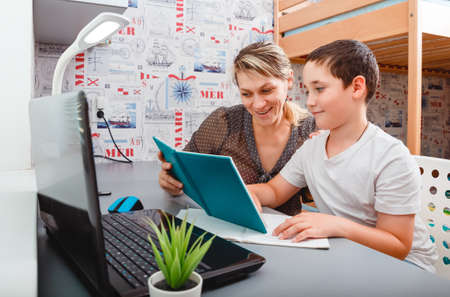 Schoolboy educate online. Mother helps his son with homework. Boy in video conference with teacher...